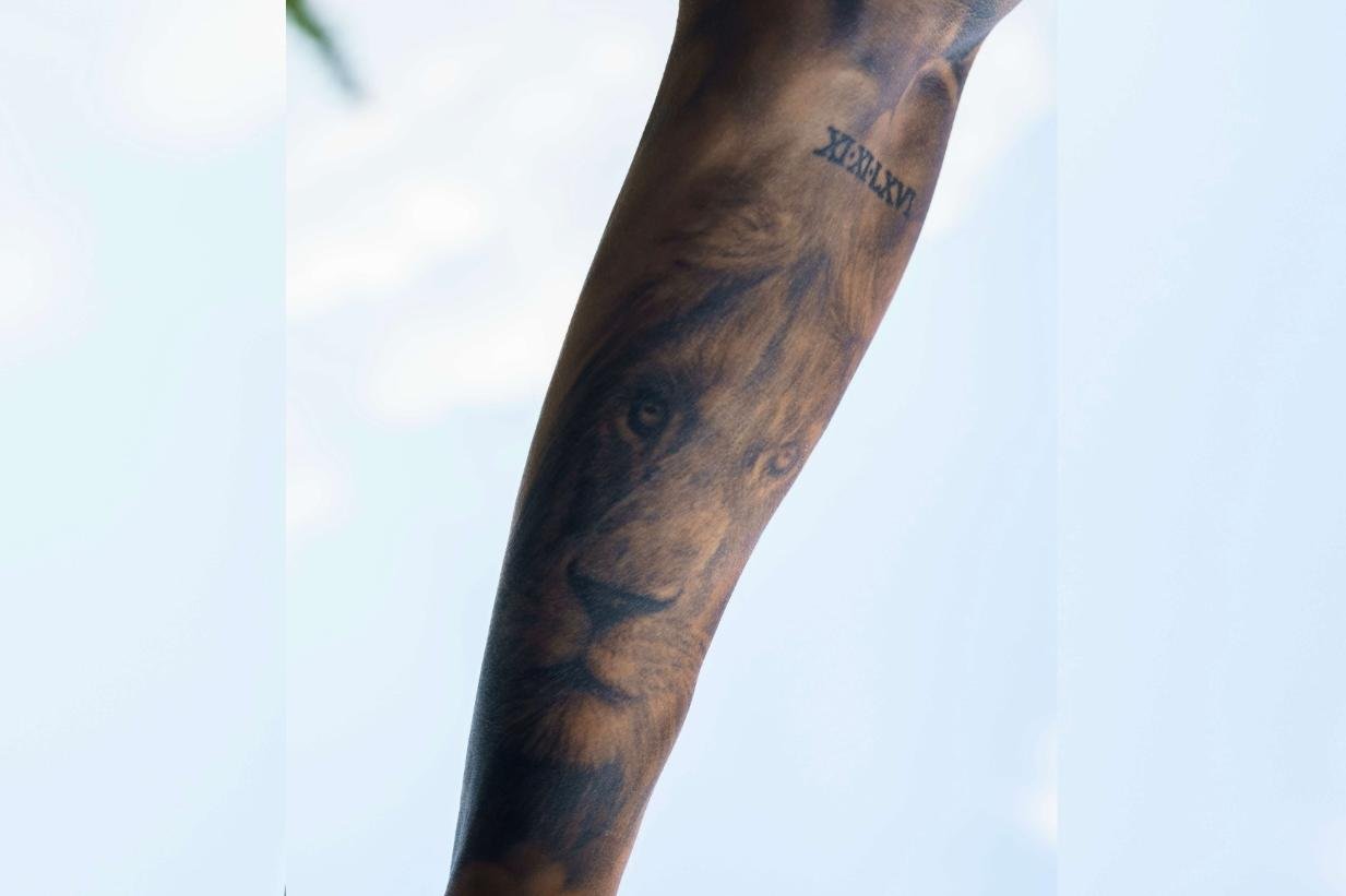 Tim Kühnel tattoos: Arm photograph documenting the lion and Roman numeral family tattoo