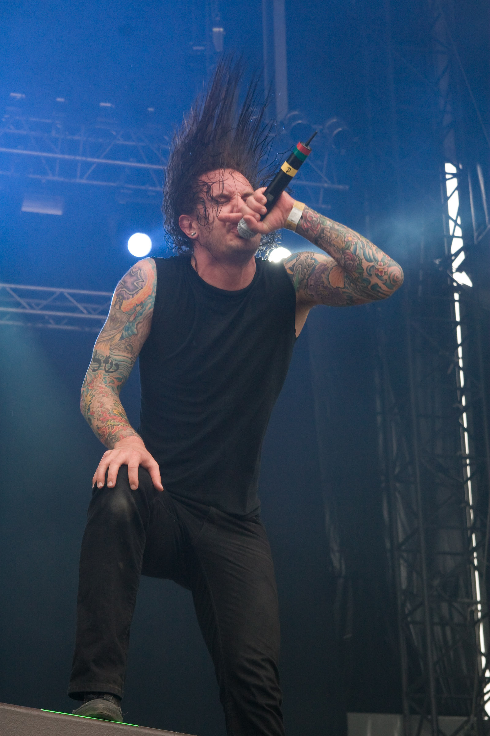 Tim Lambesis on stage with colorful arm tattoos clearly visible