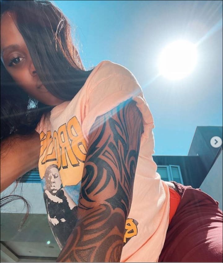 Tiwa Savage tattoos: Genuine close view of the sweeping curved bands and shading across Tiwa Savage’s upper-arm sleeve.