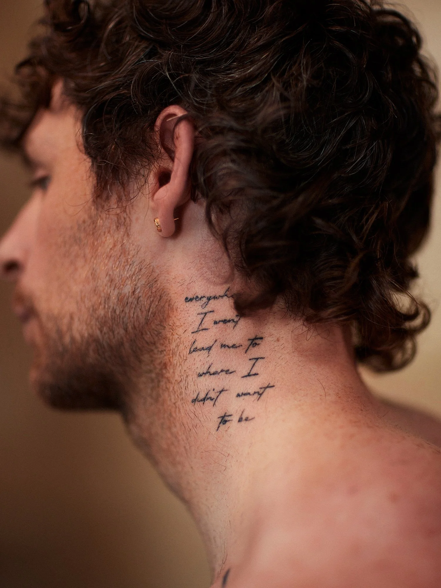 Tom Grennan tattoos: multi-line neck script