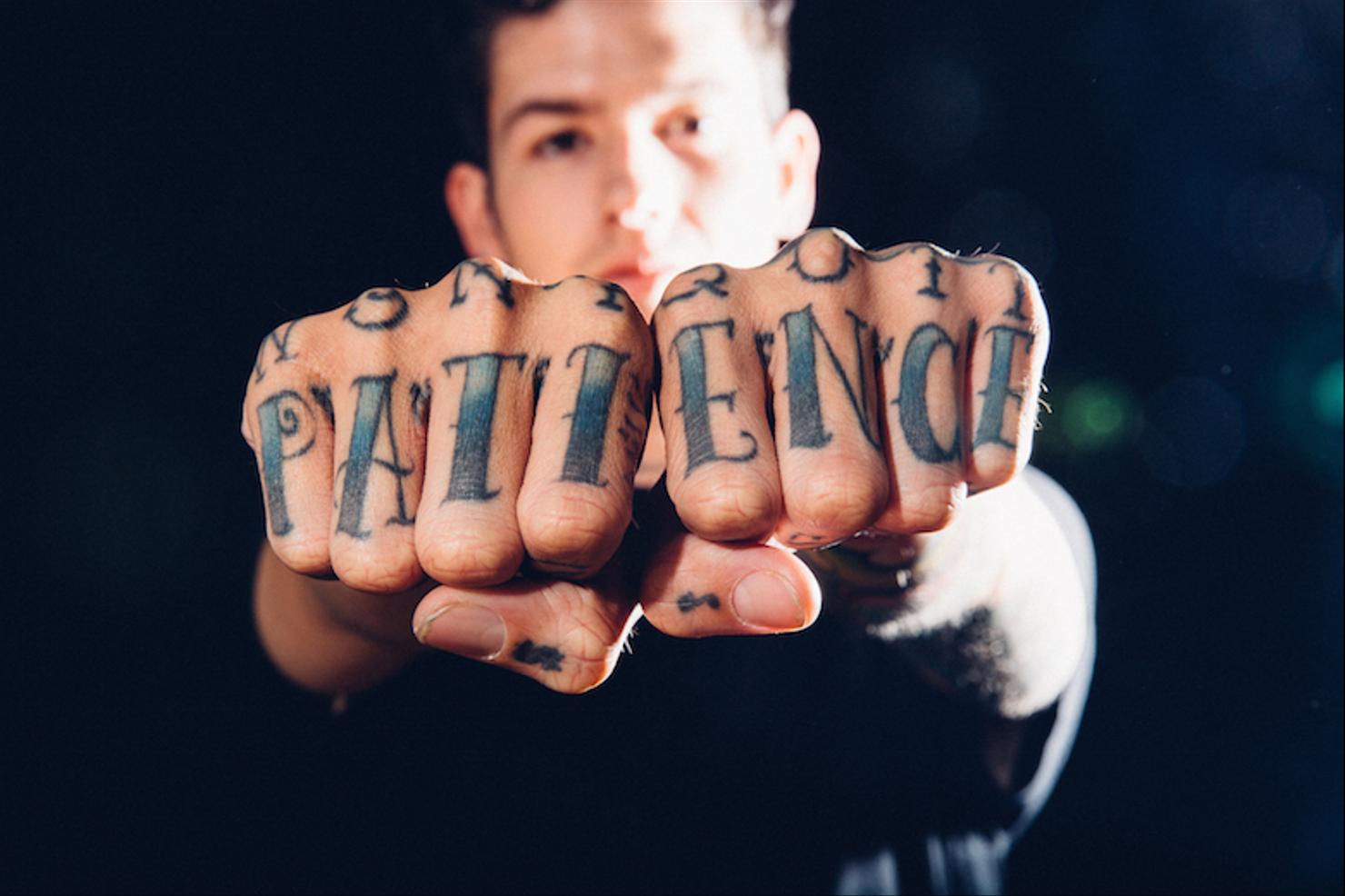 Travis Mills tattooed knuckles with Patience lettering