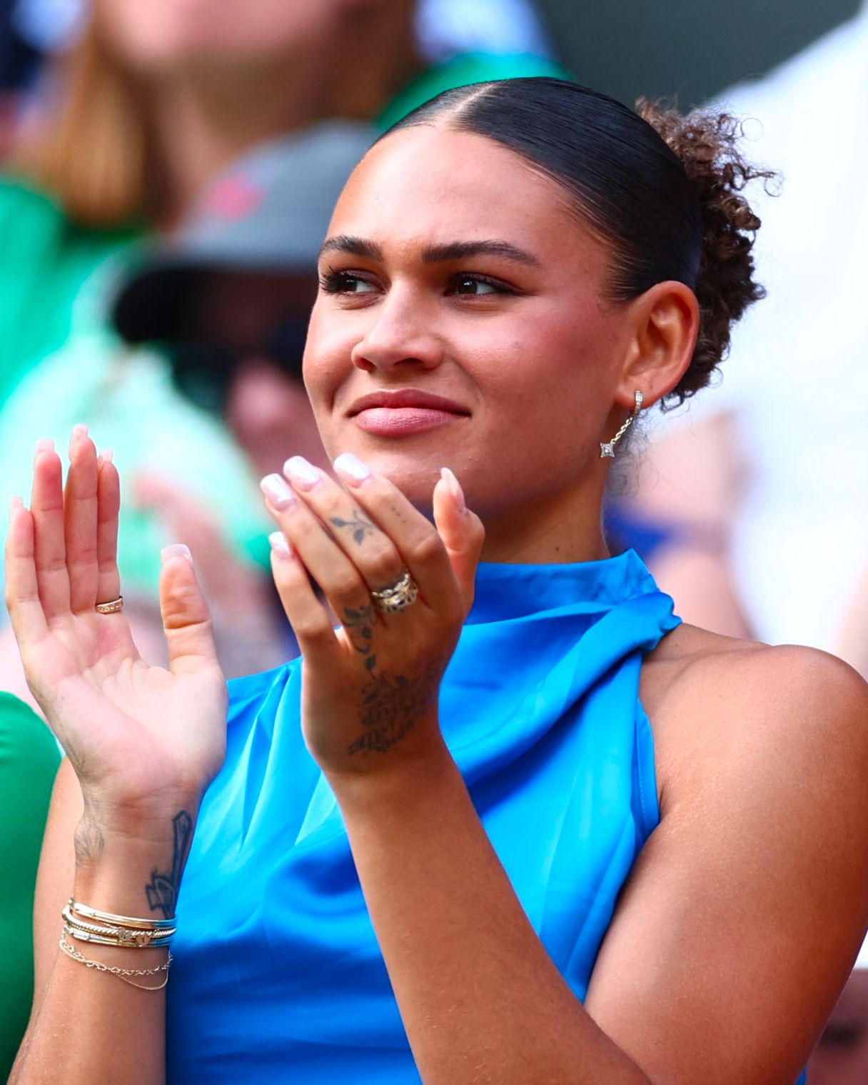Trinity Rodman tattoos: Distinct vertical event photograph showing Rodman applauding, with the wrist and hand ink visible beside her bracelets.