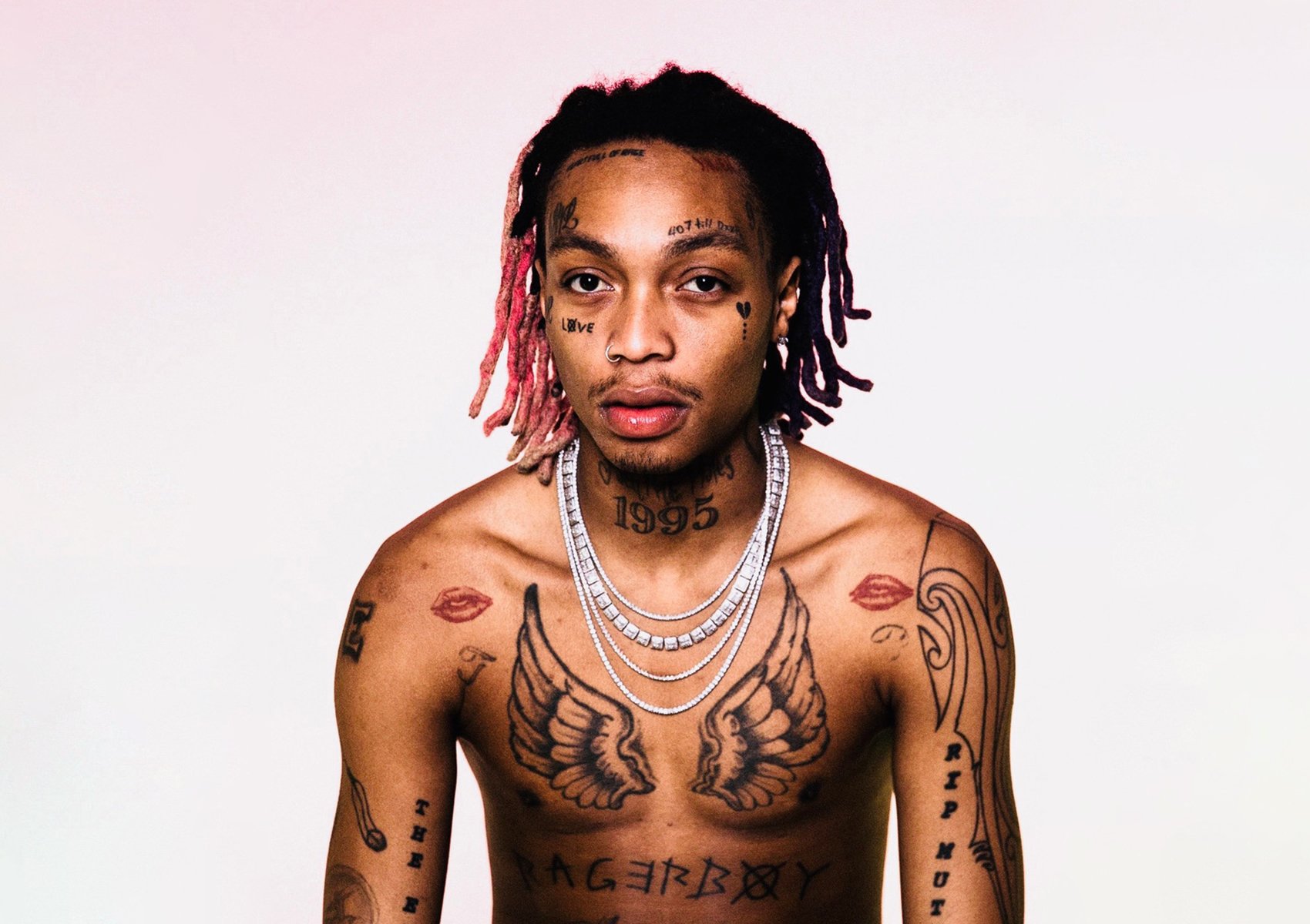 Tyla Yaweh tattoos: Good Vibes eyelid ink and chest tattoos Tyla Yaweh tattoos: Tyla Yaweh front portrait showing eyelid-area face lettering and chest ink