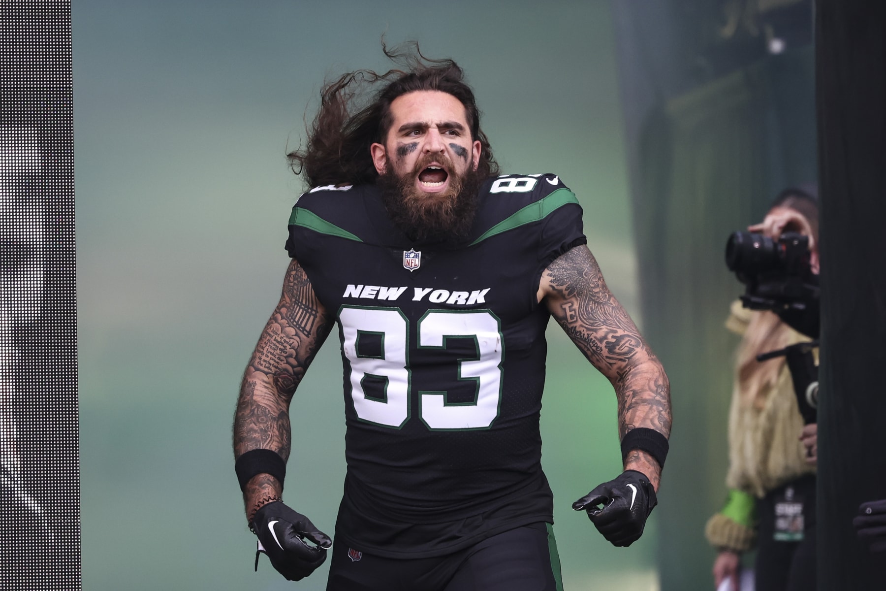 Tyler Conklin Left arm lettering and layered symbols in a separate high-resolution Jets tunnel photograph Tyler Conklin tattoos: Left arm lettering and layered symbols in a separate high-resolution Jets tunnel photograph