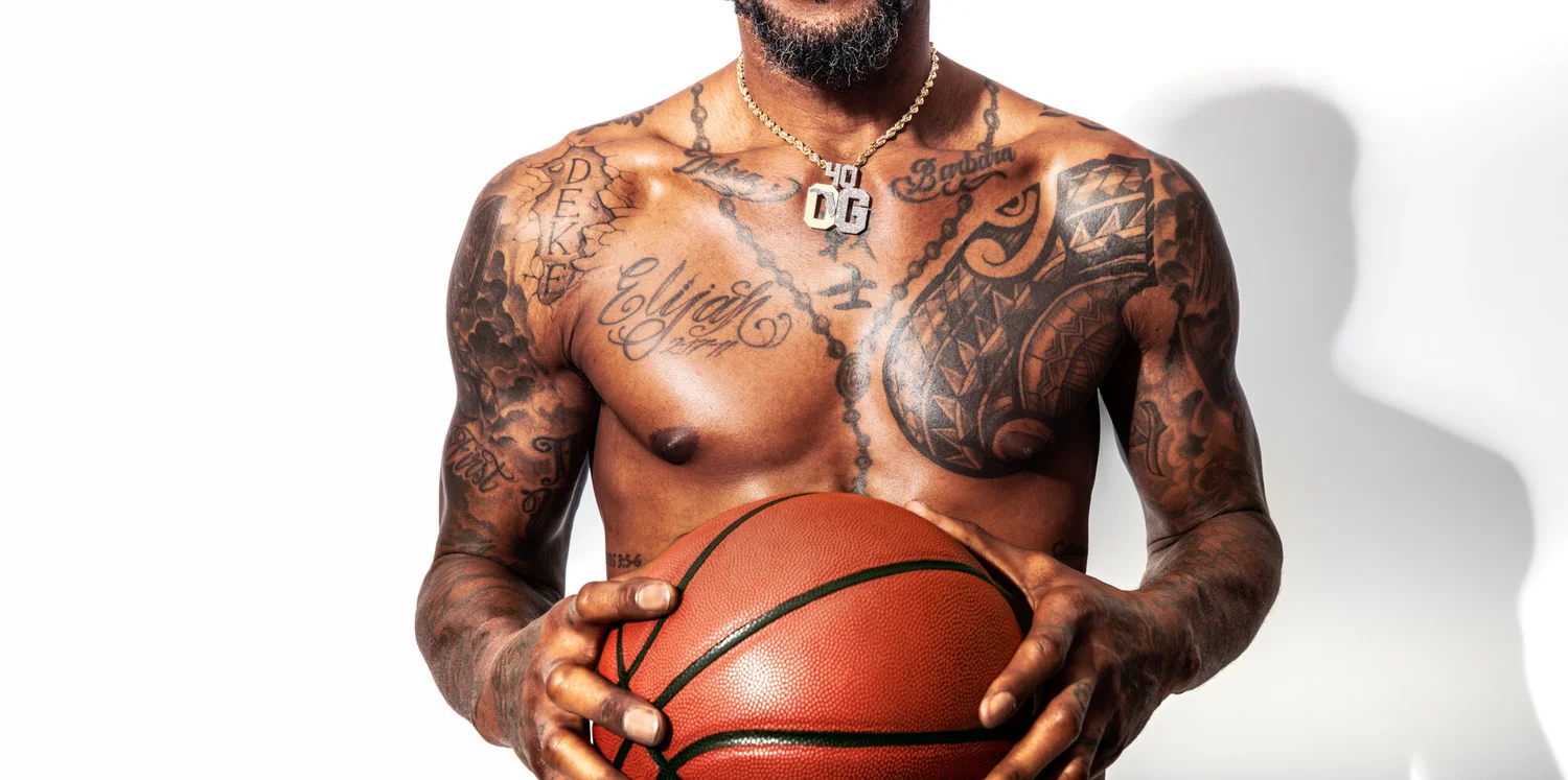 Udonis Haslem tattoos: close shirtless view showing chest script, rosary line, shoulder pattern and both arms