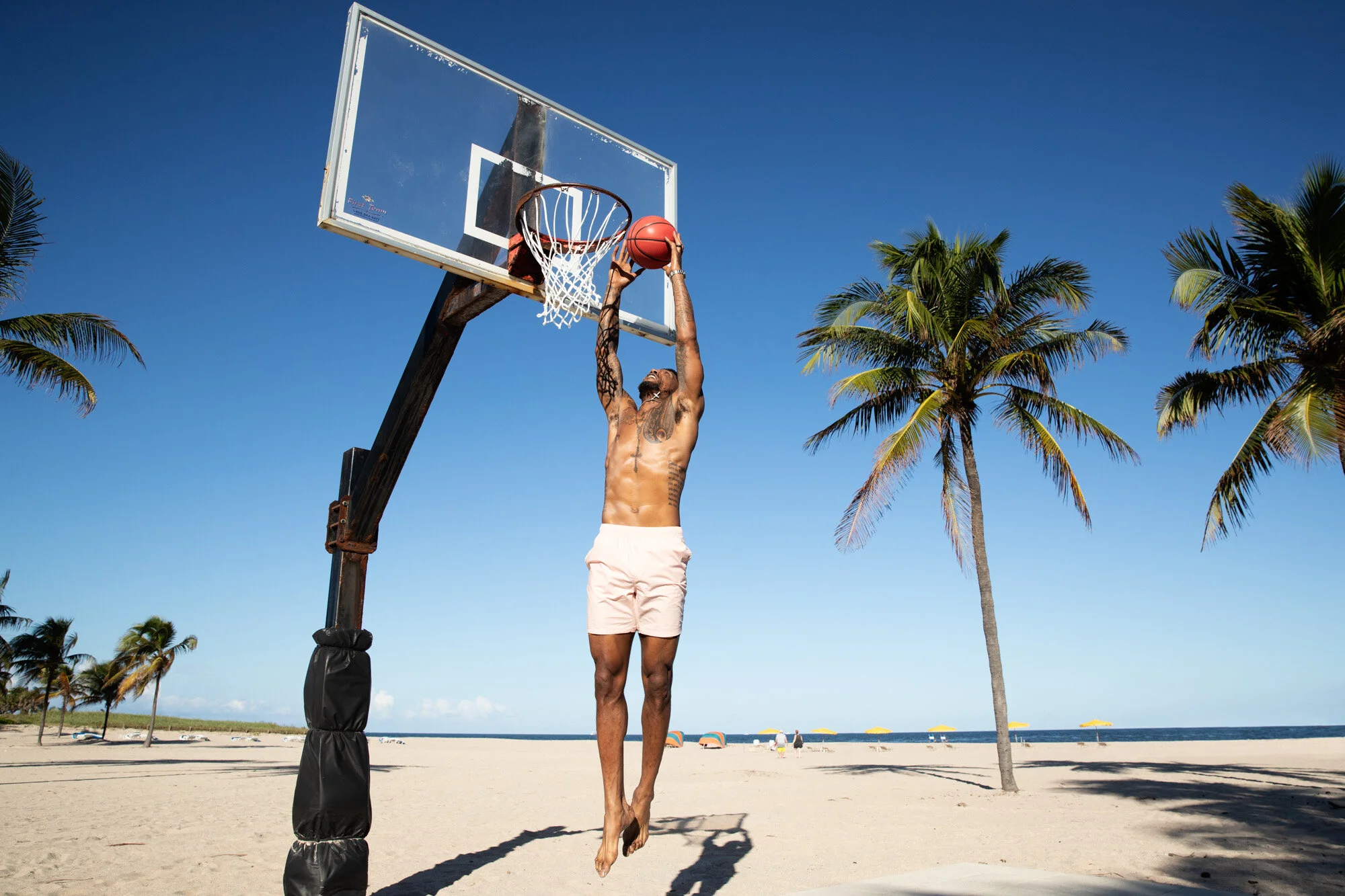 Udonis Haslem tattoos: standing shirtless view showing the chest lettering, abdominal script and arm coverage