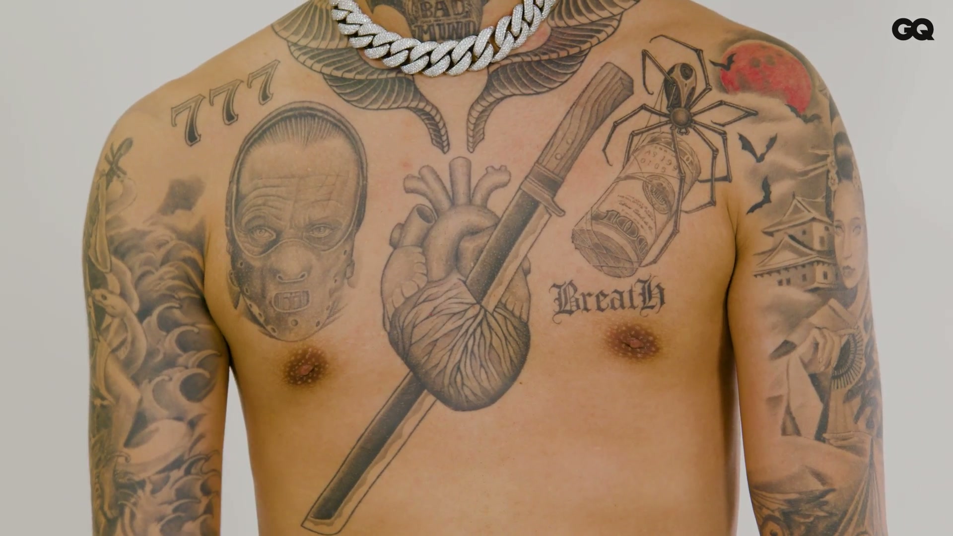 Vingo chest tattoos and central portrait Vingo tattoos: Chest close-up showing the central portrait-like figure, surrounding objects, 777 marking and Breath lettering.