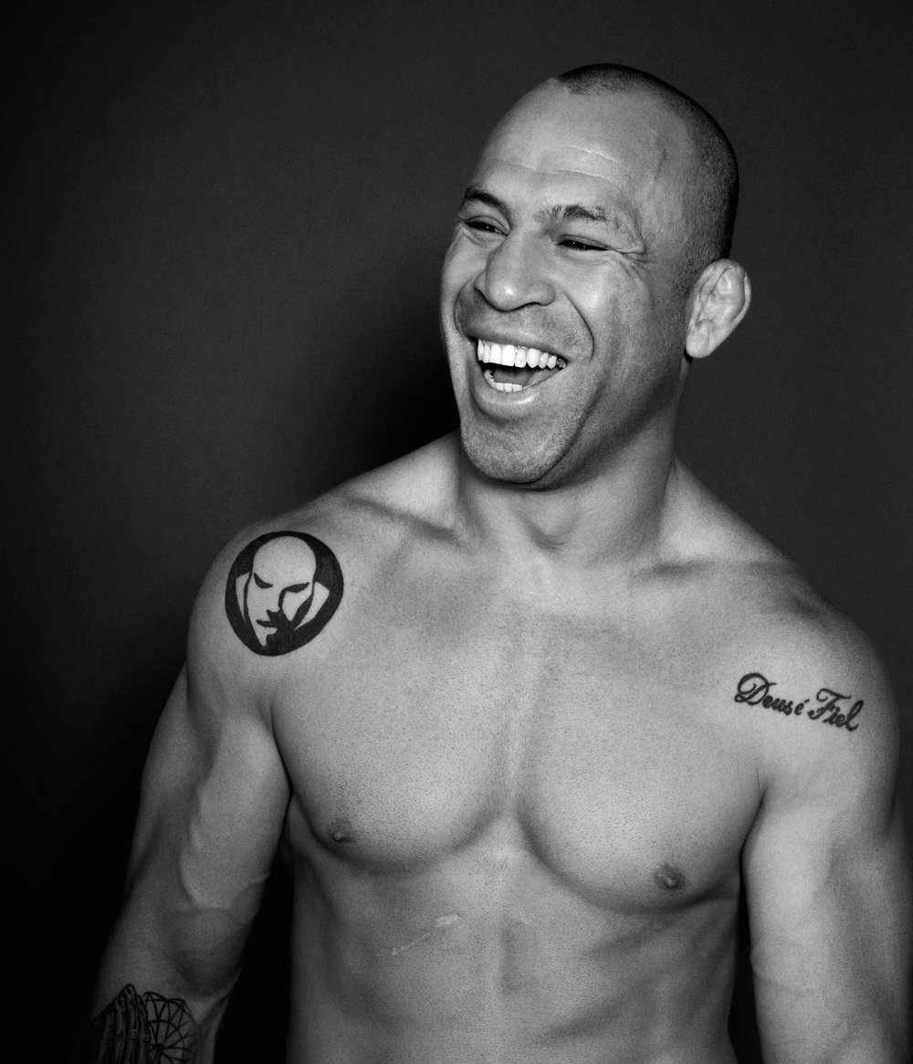 Wanderlei Silva tattoos: Wand Fight Team shoulder symbol beside the Deus é Fiel script