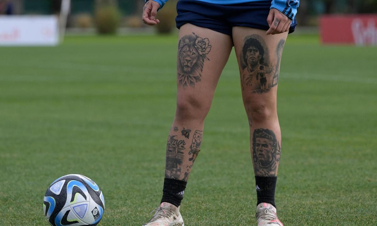 Yamila Rodriguez tattoos: Genuine single training photograph showing the football portraits, lion and Amor lettering; tattoo evidence, not contextual fallback.