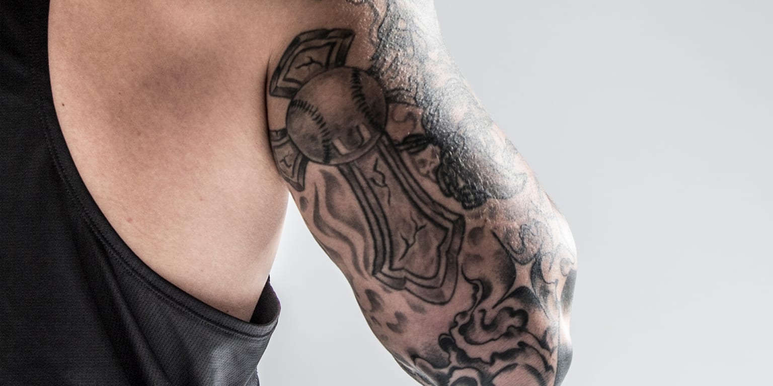 Yasmani Grandal tattoos: Close view of the right upper-arm cross, baseball and Miami U design