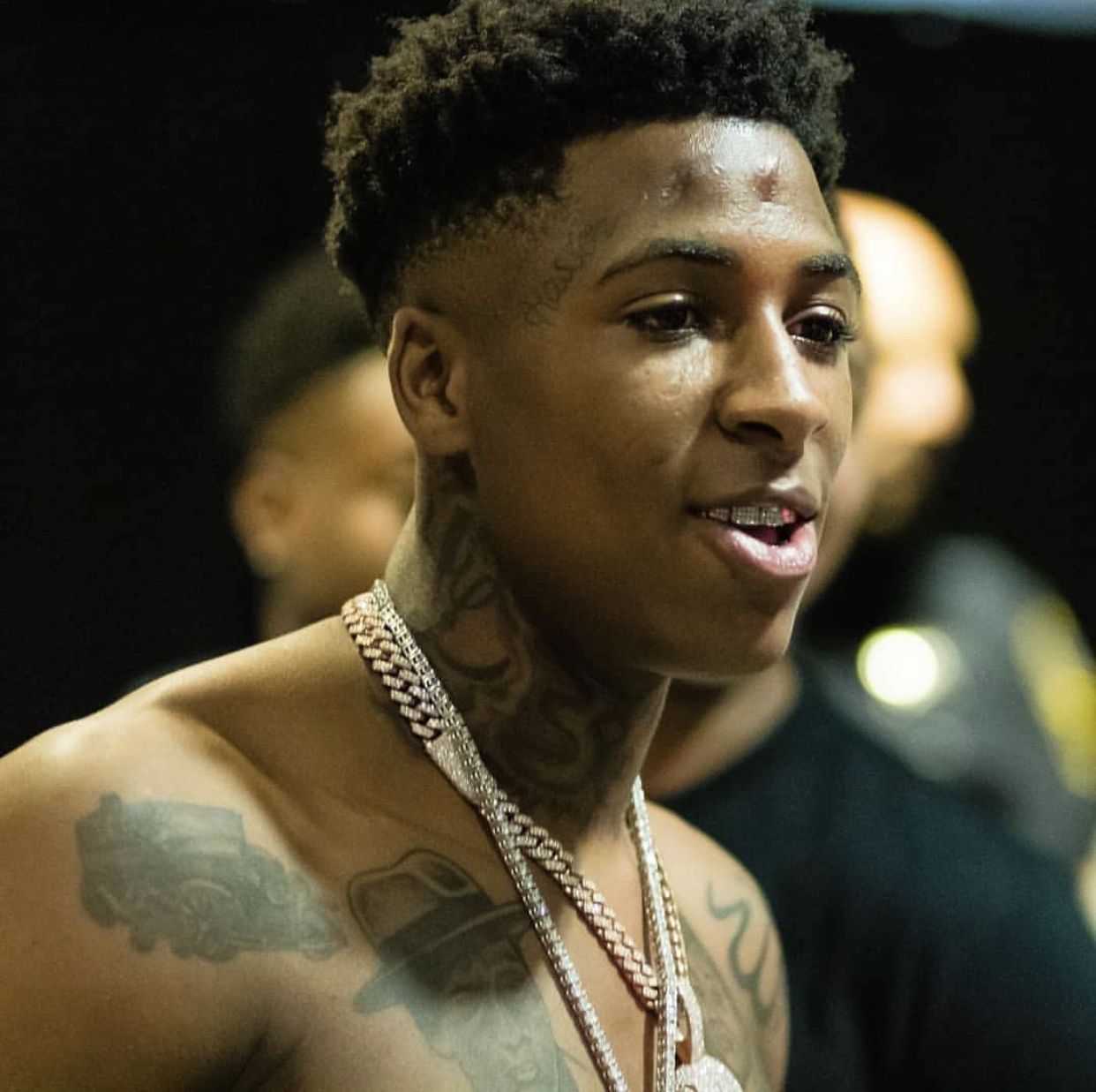 YoungBoy Never Broke Again tattoos: high-resolution backstage portrait showing face, neck, chest and shoulder tattoos