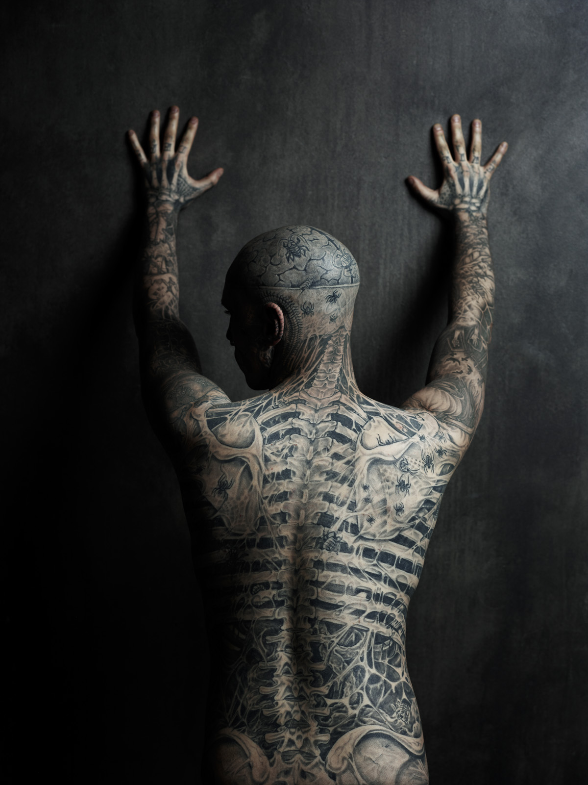 Rick Genest tattoos: distinct high-resolution rear studio view showing the spine, ribs, pelvis, shoulders, arms and back insects